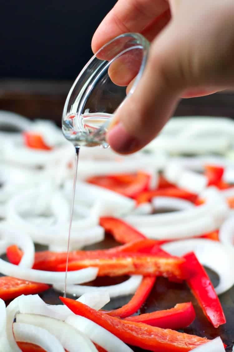 A process shot of pouring oil over vegetables to make shrimp fajitas