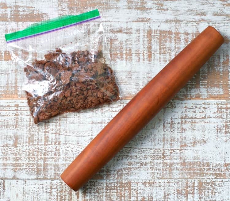 A photo of chocolate cookies and a rolling pin on a wooden surface used for making halloween yogurt cups