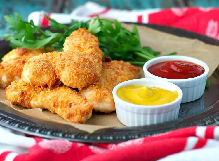 A small pile of Baked Chicken Tenders on a plate with dipping sauces