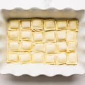 A layer of frozen ravioli in the bottom of the baking dish.