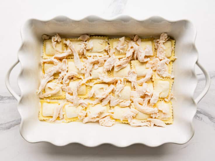 Adding a layer of chicken on top of the ravioli.