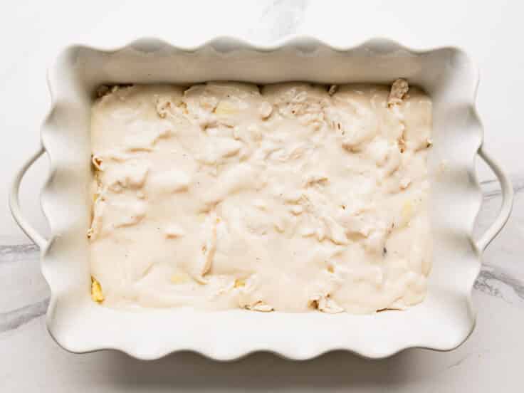 Adding a layer of Alfredo on top of the chicken and ravioli.