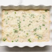 Adding the peas and cheese to the top of the dish.