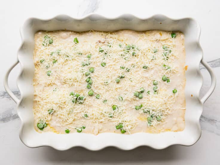 Adding the peas and cheese to the top of the dish.