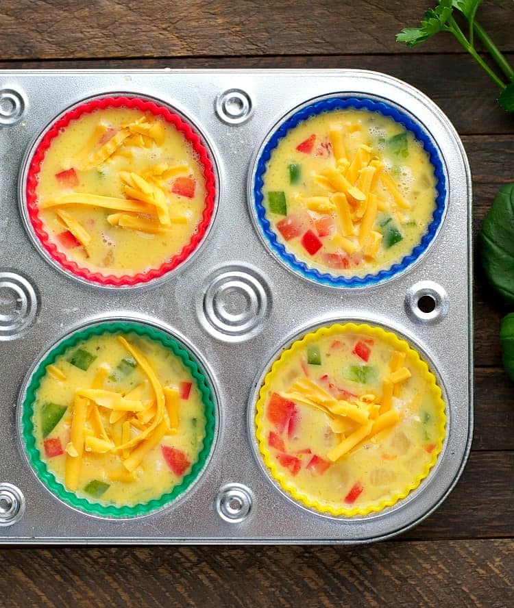 An overhead image of the liquid egg mixture poured into a muffin tin, each cup lined with a reusable silicone muffin liner.