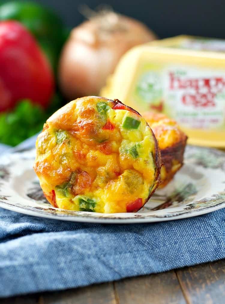 A close up of egg muffins on a small plate with a carton of eggs in the background