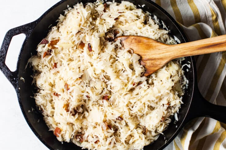 Heating sauerkraut in bacon drippings in a cast iron pan.