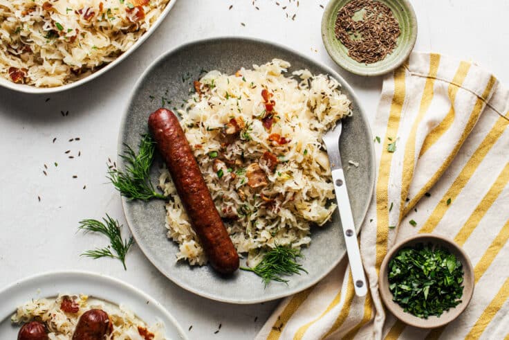 Horizontal overhead image of a plate of sauerkraut with sausage.