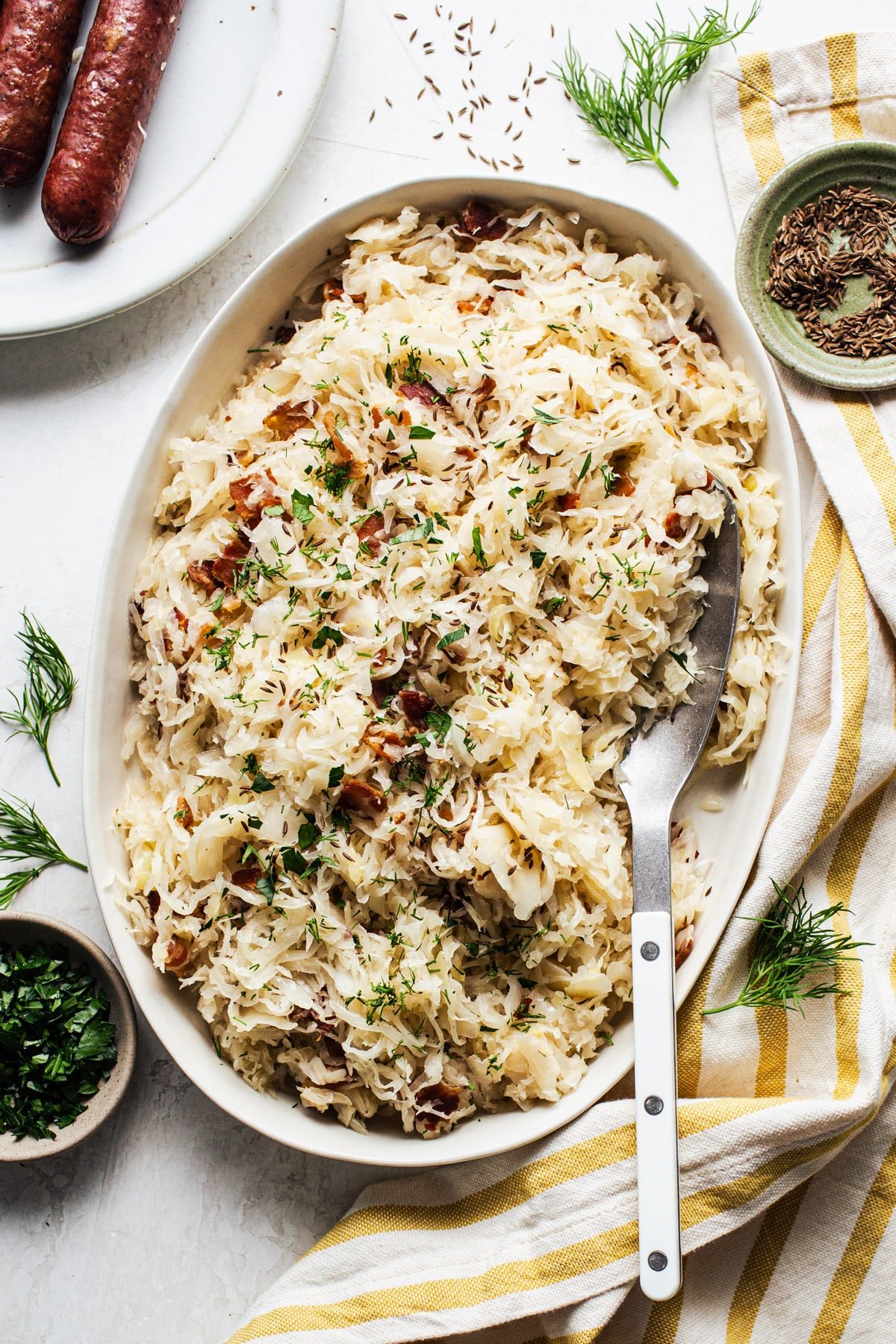 Sauerkraut with bacon in a white oval serving dish.