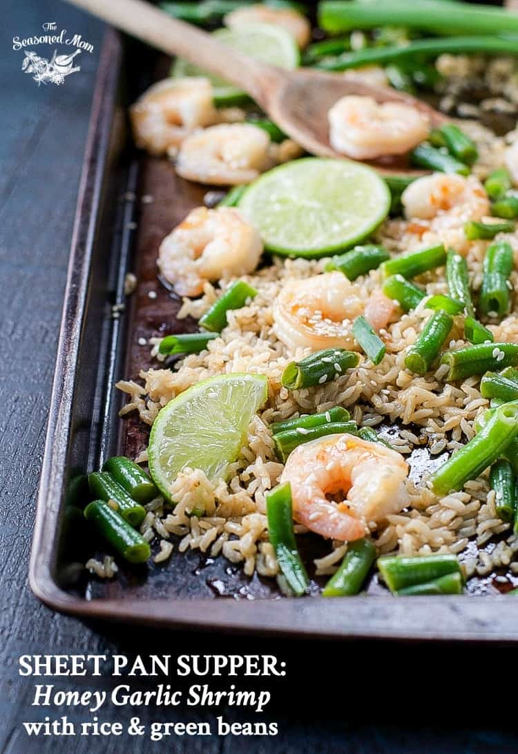 A sheet pan with honey garlic shrimp, rice and green beans on it