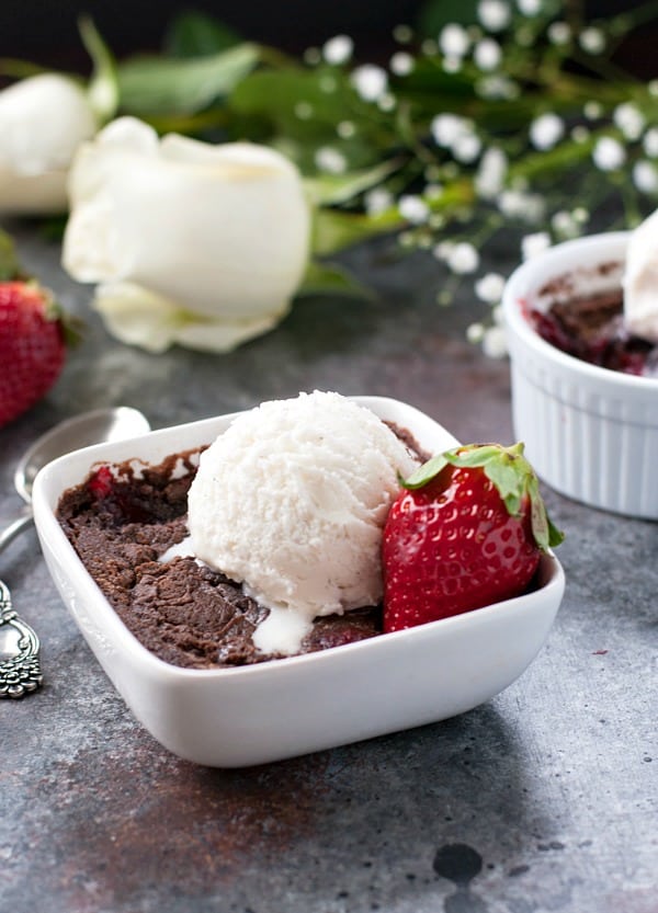 Strawberry chocolate dump cake for two in white bowl with ice cream and strawberry on top