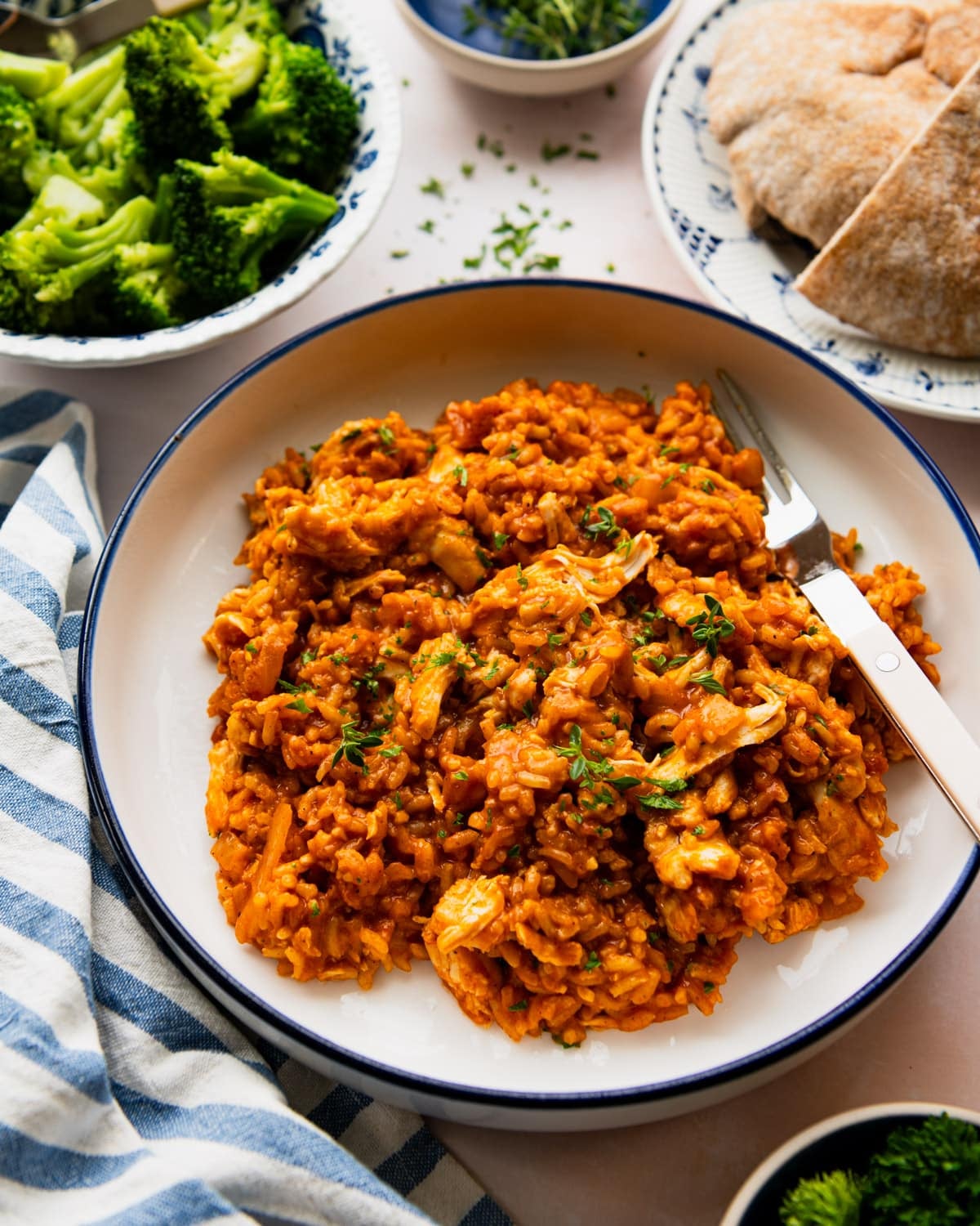 Side shot of butter chicken and rice in a white bowl with a blue trim.