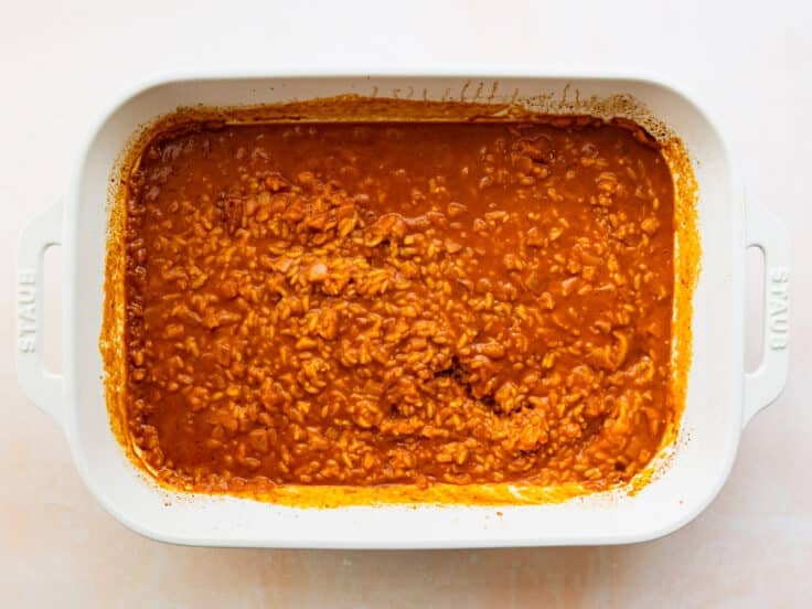Removing the cover from the partially cooked casserole.