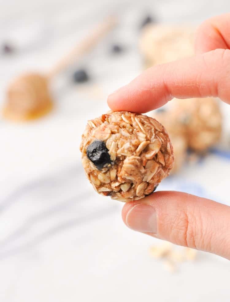 A close up of a hand holding a blueberry and almond energy snack