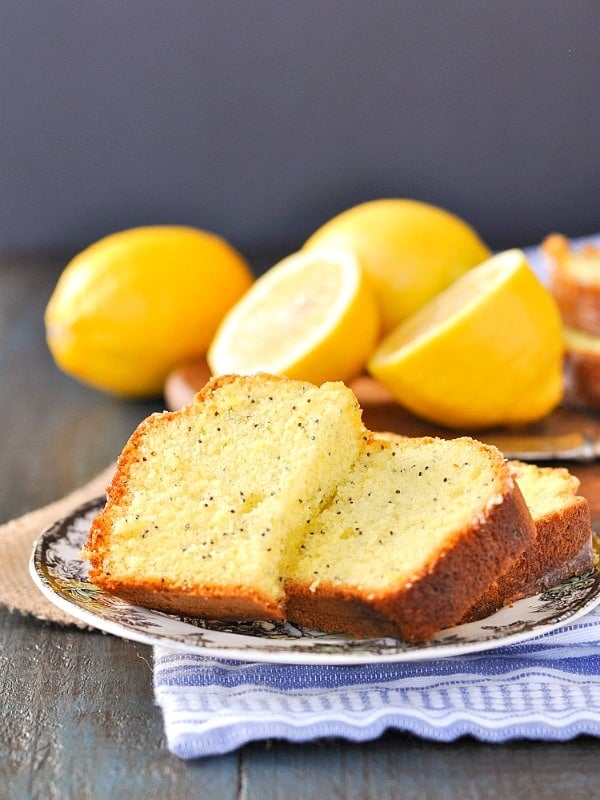 Slices of lemon bread on a plate with fresh lemons in the background