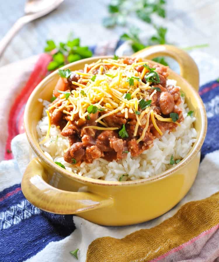 Rice and beans in a yellow bowl topped with grated cheese and herbs