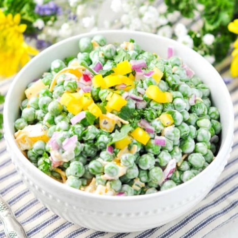 Southern pea salad in a white bowl surrounded by fresh flowers