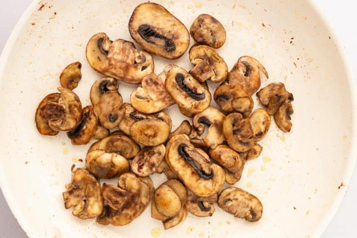 Sauting sliced mushrooms in a skillet.