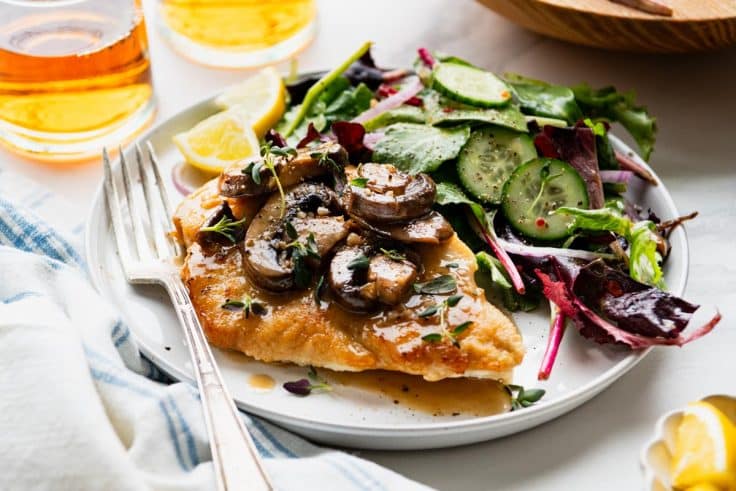Horizontal shot of an easy chicken marsala recipe served on a white plate.