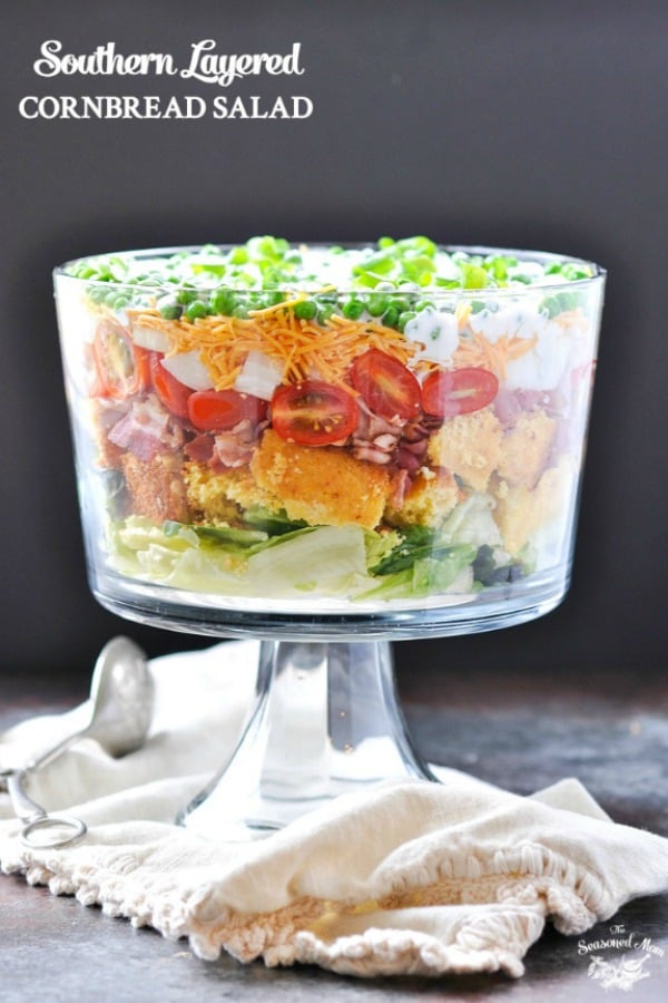 Layered Southern Cornbread Salad with bacon and cheese in a large glass serving bowl