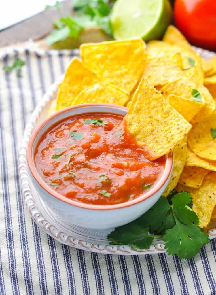A small bowl of homemade salsa with chips at the side