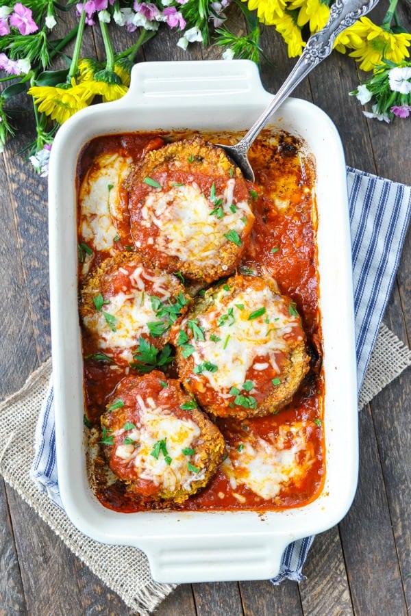 Overhead shot of baked eggplant parmesan in a baking dish garnished with parsley