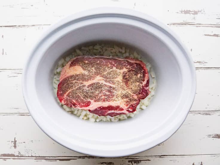 Adding the chuck roast to the slow cooker.