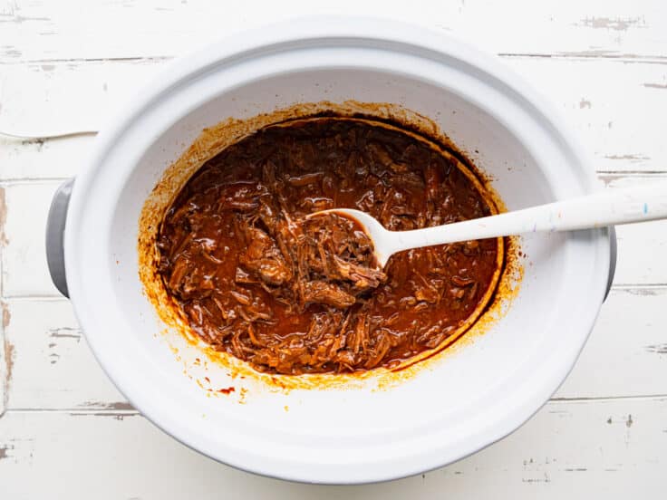 Stirring the shredded beef back into the sauce.