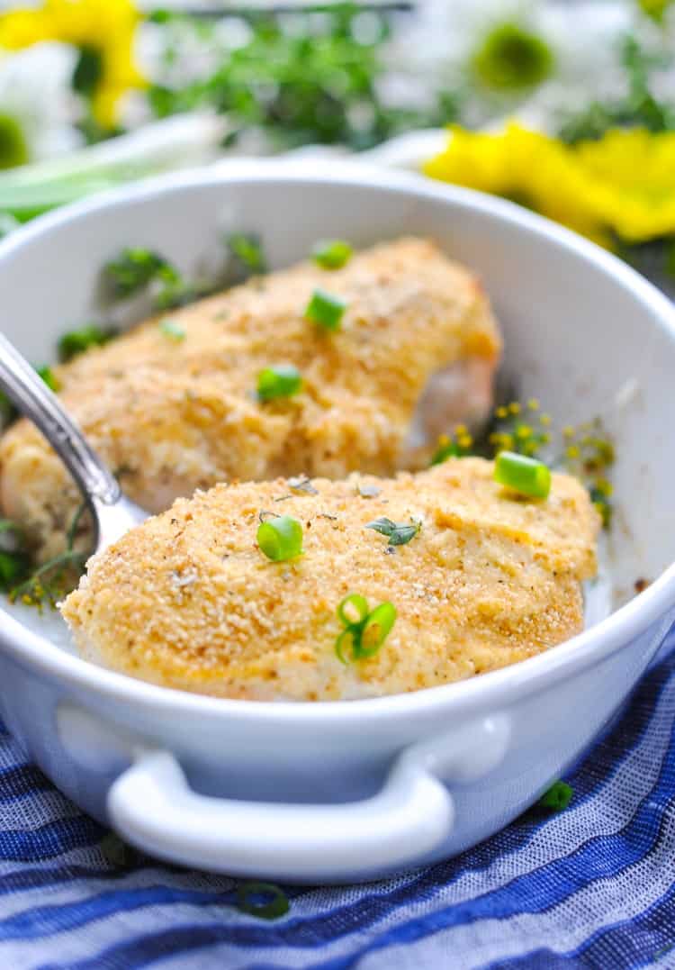 A close up of parmesan smothered chicken in a baking dish