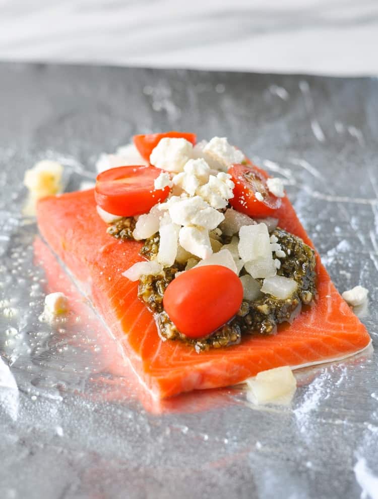 A fillet of salmon in foil topped with Mediterranean ingredients