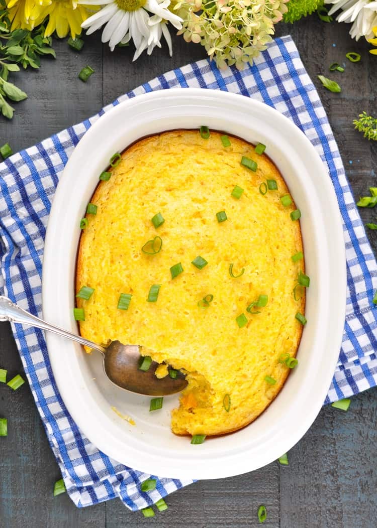 An overhead shot of corn pudding with green onions scattered over the top