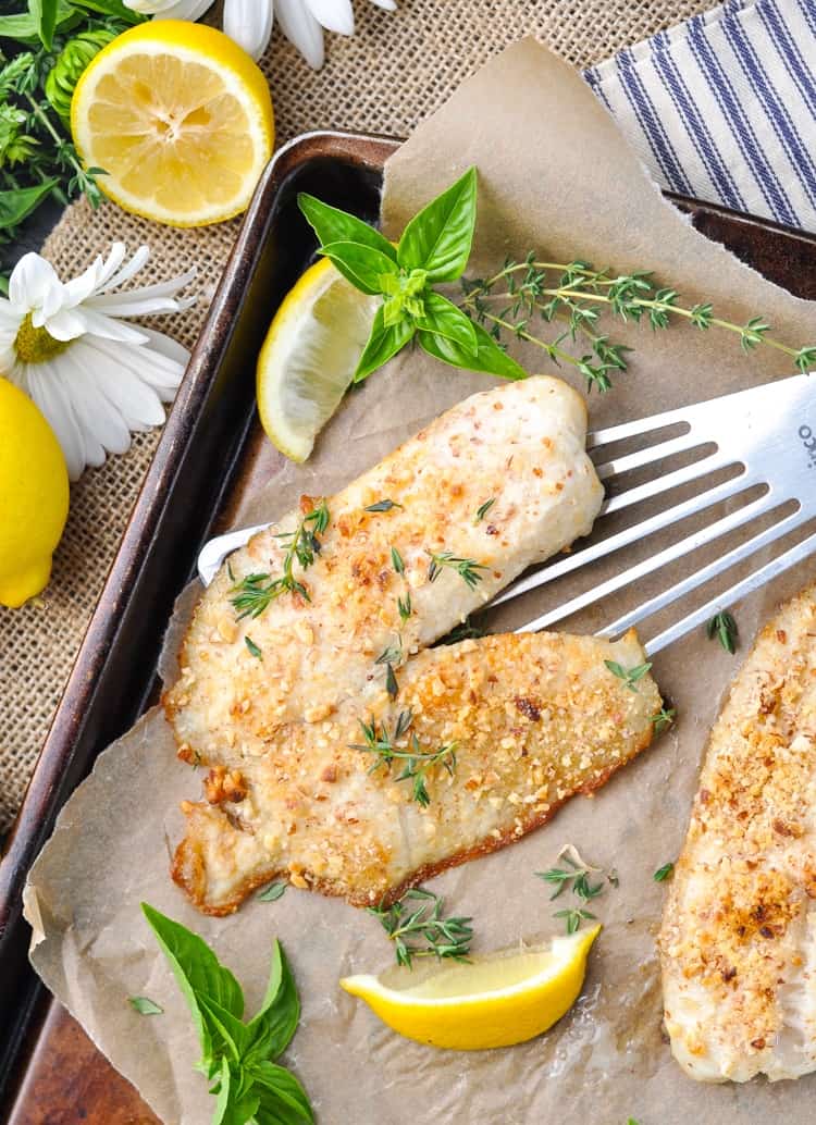 Baked Tilapia on a baking tray with lemon wedges