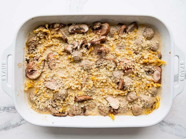 Adding the breadcrumb topping to a beef stroganoff casserole.