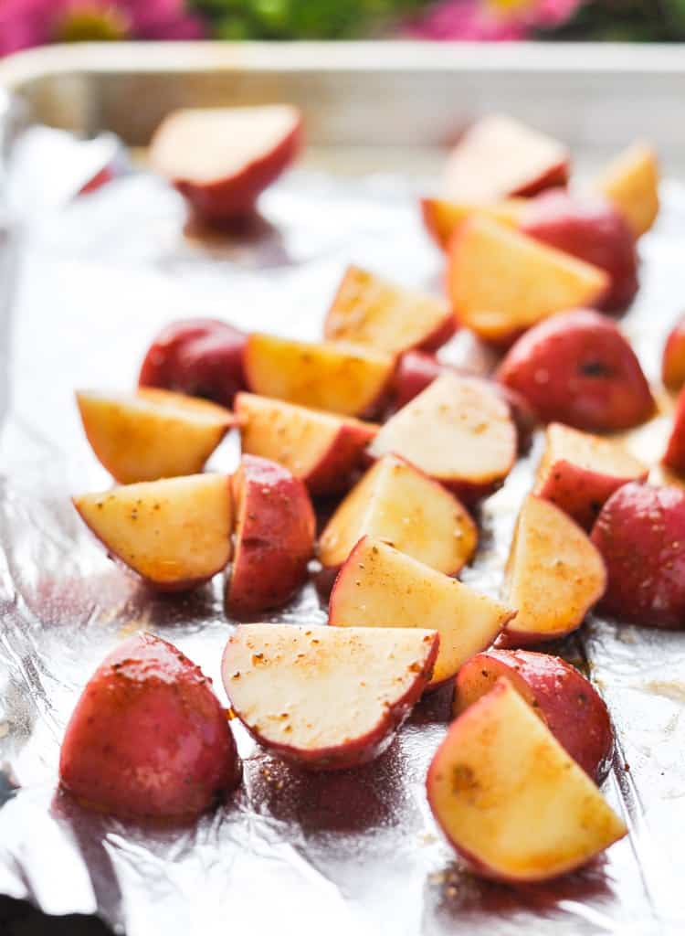 seasoned red potatoes in a roasting pan ready to be roasted