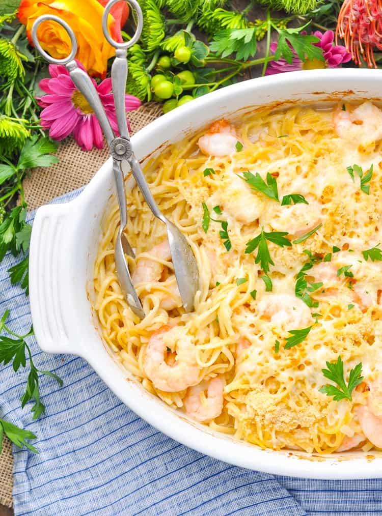 Shrimp scampi linguine in an oval dish with serving spoons