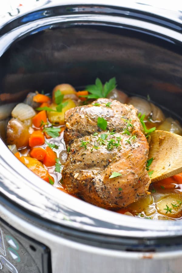 Slow cooker pork topped with fresh green herbs.