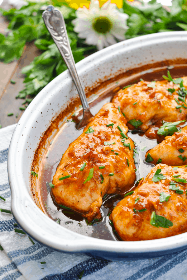 Baked chicken breasts in a honey french sauce in a casserole dish with sliced green onion on top