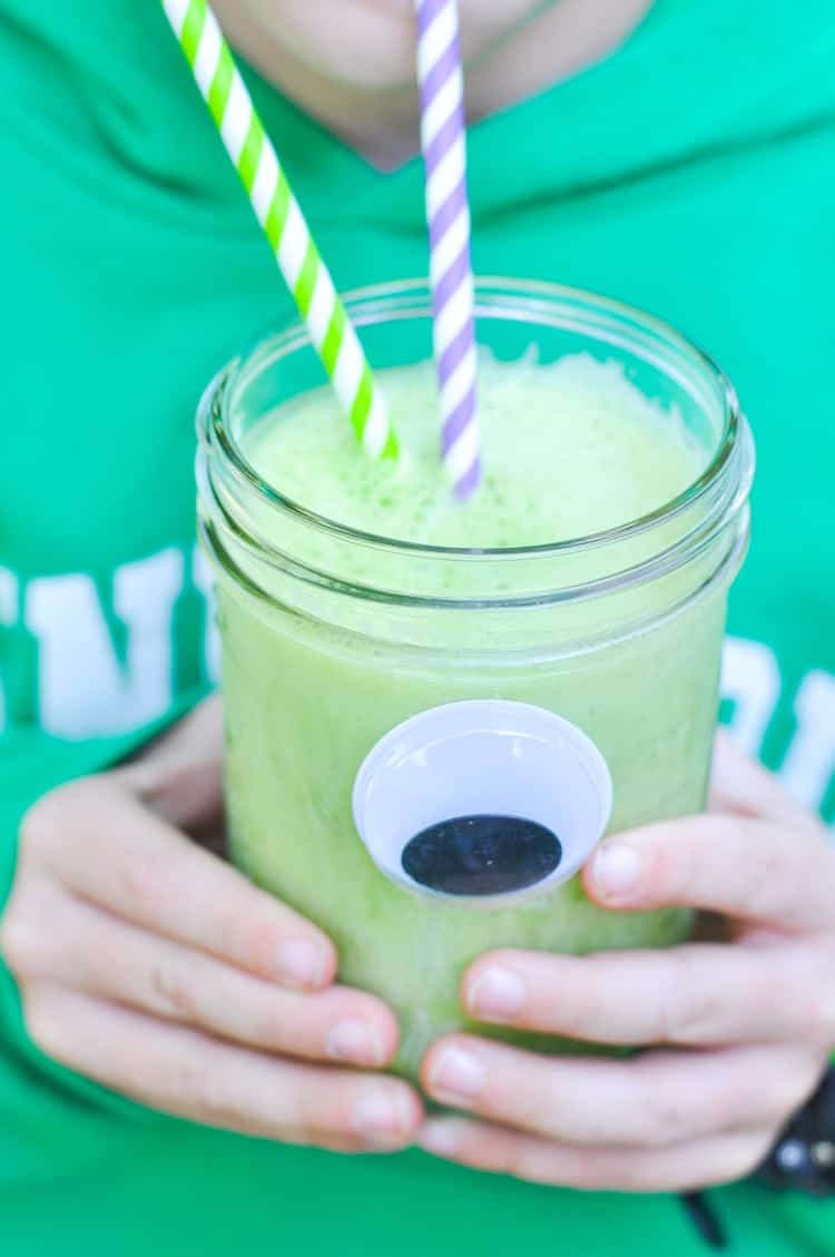 A close up of two hands holding a monster green smoothie