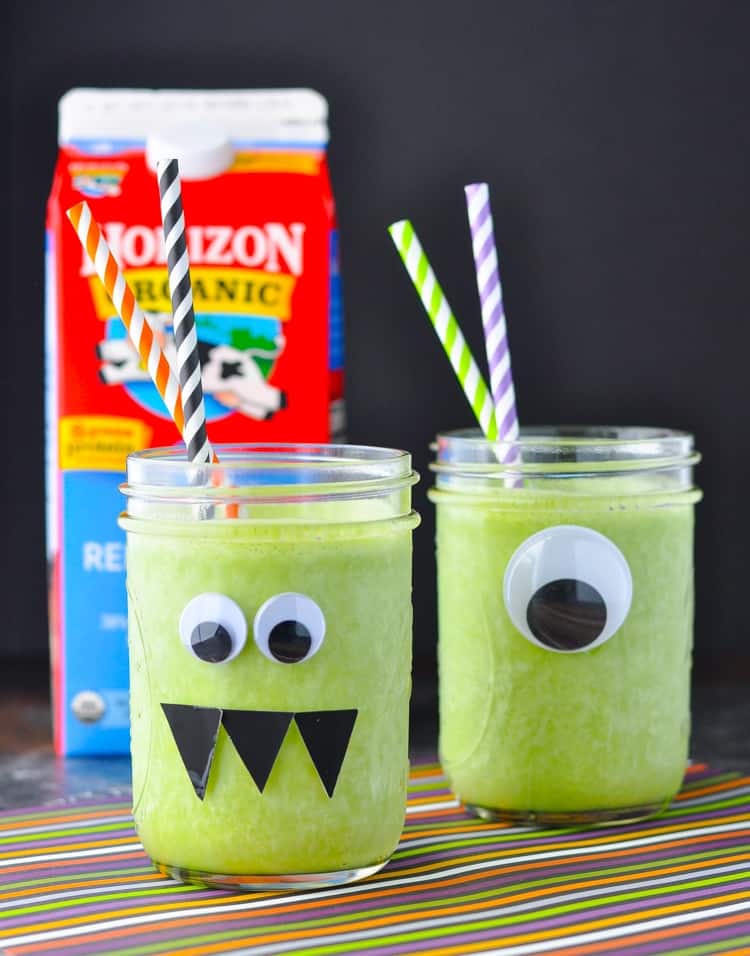 Two mason jars filled with a 4-ingredient monster green smoothie with a carton of milk in the background