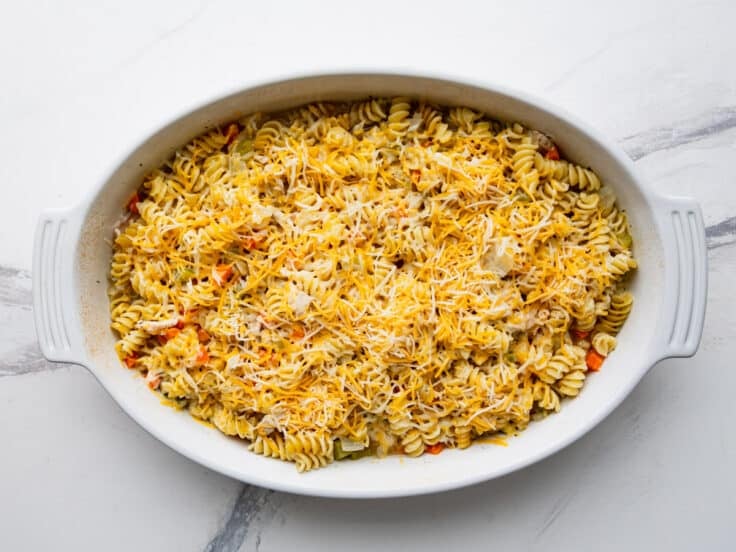 Adding cheese to the top of a dump and bake chicken noodle casserole.