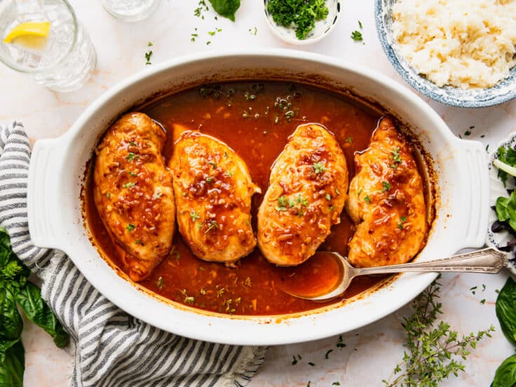 Horizontal overhead shot of baked honey chicken breasts in a white dish.