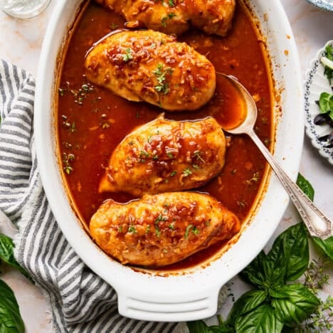 Square overhead shot of baked honey chicken breasts in a white dish.