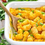 A side shot of a tater tots casserole with a wooden spoon