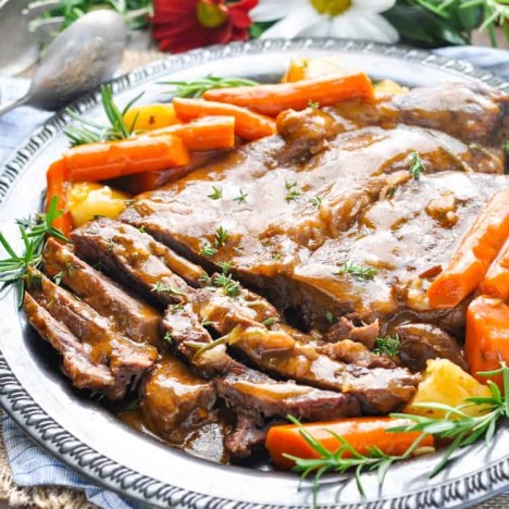 A classic pot roast on a serving plate with veggies