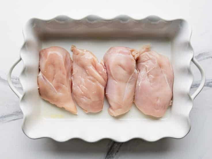 Boneless skinless chicken breasts in a baking dish.