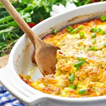 Bacon sausage and egg casserole in a white dish with wooden spoon