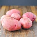 Whole unpeeled red potatoes on a wooden surface