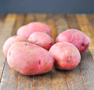 Whole unpeeled red potatoes on a wooden surface