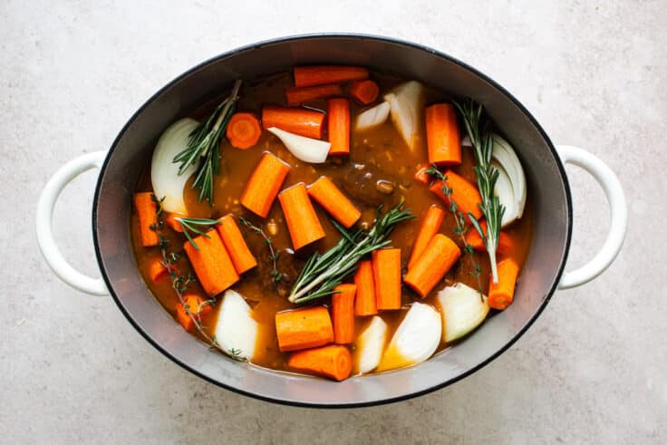 Ingredients for a classic slow cooker pot roast recipe in the pot before cooking.