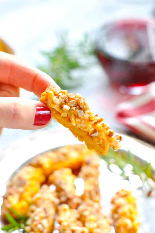 Fingers holding a cheese straws appetizer